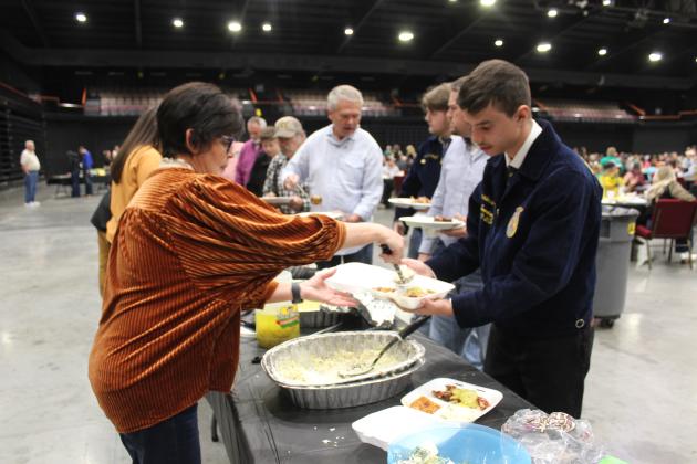 Terrie Dugan, the grandmother of both 4-H and FFA students, serves coleslaw to Macomb FFA student Amadeus Sandifer at the Pottawatomie County Junior Livestock Show Pig Roast, held at FireLake Arena on Feb. 3. Countywide &amp; Sun/Natasha Dunagan