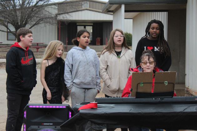 Macomb choir students Kaesyn Schooler, Autumn Burk, Tierra Gunsolus, Audrey Wilmoth and Lyric'Rose Hendley sing the national anthem, as their teacher Kathy Holsonbake plays the keyboard during the grand opening of the new Macomb Elementary School playground on Feb. 6. Countywide &amp; Sun/Natasha Dunagan