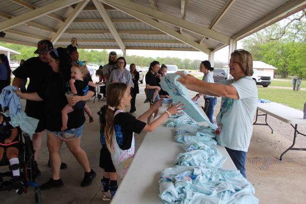 Citizen Potawatomi Nation (CPN) Indian Child Welfare Preservation Coordinator Heather Calton hands a T-shirt to a girl at the Sixth Annual Child Abuse Prevention Walk, held at the CPN Festival Grounds on April 18. The event is hosted by FireLodge Children &amp; Family Services and had 165 participants this year. Natasha Dunagan, Countywide &amp; Sun