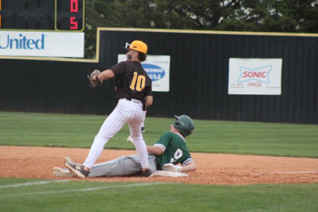 Tecumseh senior Caleb Sparks throws back to the pitcher after a Seminole runner dives back to first in the April 14 home game. The Savages won, 8-0.