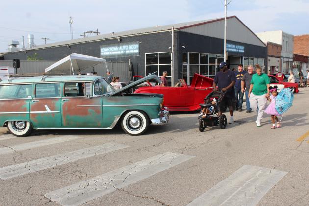 A family walks by several classic vehicles at the Downtown Auto at Sundown Car Show in Shawnee on June 14.