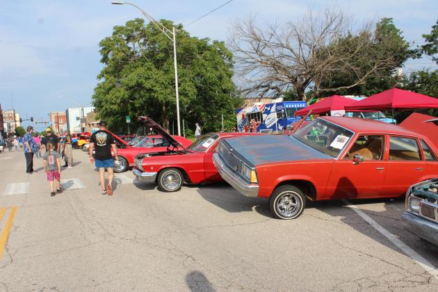 A 1980 Chevy Malibu, owned by Billy Roll,  with hydraulics sits an angle among other red cars at the Downtown Auto at Sundown Car Show in Shawnee on June 14.