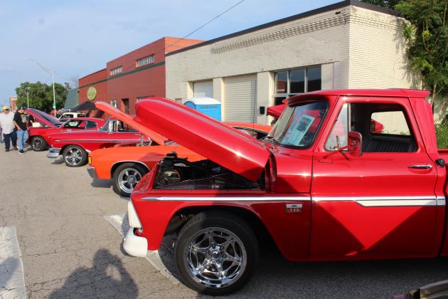 A 1966 Chevy C-10, belonging to Randy and Lisa Schultz, stands in the foreground of a line of red and orange vehicles at the Downtown Auto at Sundown Car Show in Shawnee on June 14.