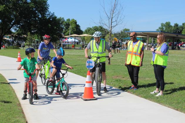 Travis Hurst, with Kids Action, center, talks with three young bicyclists, as John Bobb-Semple with Pottawatomie Go (POGO) and Built Environment Co-Chair Amanda Johnson look on, during the Bike Safety Blitz at the Fun Day at Kidspace Park in Shawnee on May 30. Fun Day was part of Health Week, which is sponsored by the Avedis Foundation, and offered a variety of activities in the morning and evening.