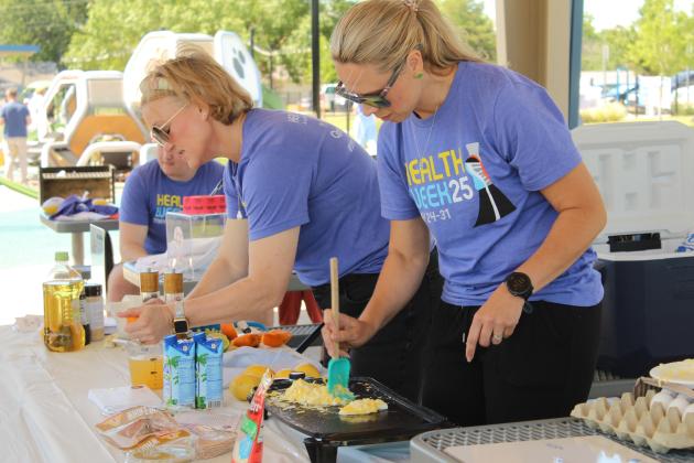 Lindsay Goodson, with Pottawatomie Go (POGO), squeezes orange juice, and Registered Dietician Andrea Beck cooks eggs for breakfast burritos during a cooking demonstration at the Fun Day at Kidspace Park on May 30. Fun Day was part of Health Week, which is sponsored by the Avedis Foundation, and offered a variety of activities in the morning and evening. Several of the events were sponsored by POGO.
