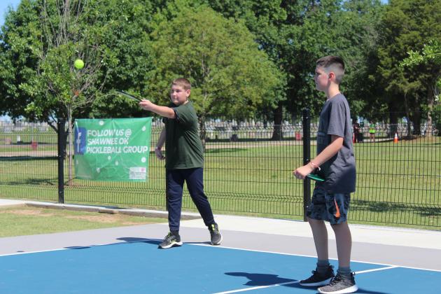 Kaesyn Schooler, 12, and Deaton Holt, 10, both of Shawnee, learn how to play pickleball from Shawnee Parks and Recreation volunteer Craig Noble, not shown, during the Fun Day at Kidspace Park on May 30.