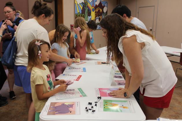 Shawnee Public Library Associate Heather Blake talks with her daughter, Alice Blake, 7, about buying a pet Tortoise with play money during the "Pet Cents" event on June 14. The library received an ALA grant to teach children how to manage money. Their next event, "Making Moo-La," will be June 21 at 10:30 am.