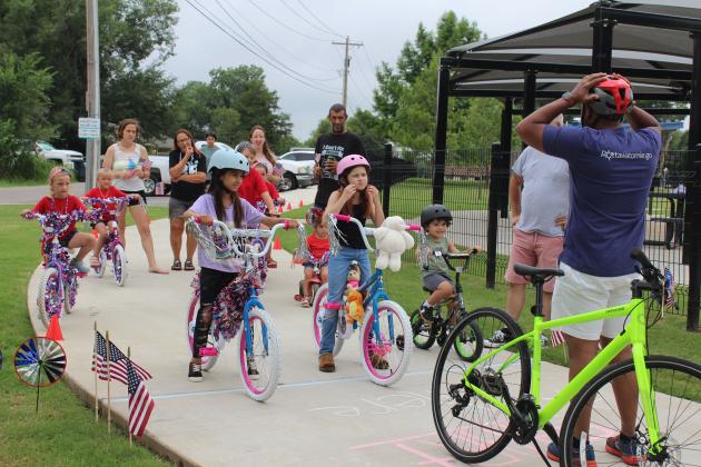 Pottawatomie Go (POGO) Executive Director John Bobb-Semple reminds participants in the Freedom Fest kids' parade to check their helmets before he leads them around Kidspace Park, as the parade marshal, on July 5. The First Annual Freedom Fest was hosted by POGO and Shawnee Parks and Recreation. They gave prizes for Most Patriotic, Most Enthusiastic and Most Creative. They also had a sidewalk chalk art contest.