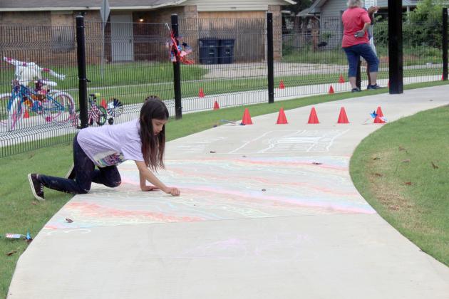 Prestynn Neely, 8, of Shawnee, works on her sidewalk chalk art entry during Freedom Fest at Kidspace Park on July 5. Her sister, Peyton Neely, 10, drew the White House behind her. The first annual event was hosted by Shawnee Parks and Recreation and Pottawatomie Go. They also held a kids' parade.