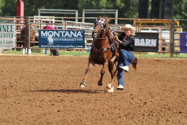 Rianne Tinsley of Shawnee dismounts her horse with a rope in her mouth ready to tie a goat during the International Finals Youth Rodeo on the morning of July 7.