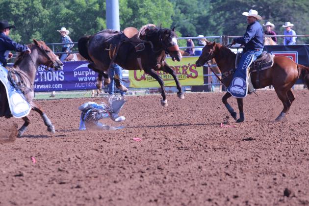 Jack Crews of St. Cloud, FL, is bucked from his horse and leaves one boot hanging in mid-air, as the horse wranglers ride in to help, during the saddle bronc event of the 33rd Annual IFYR, held at the Heart of Oklahoma Expo Center on the morning of July 8.