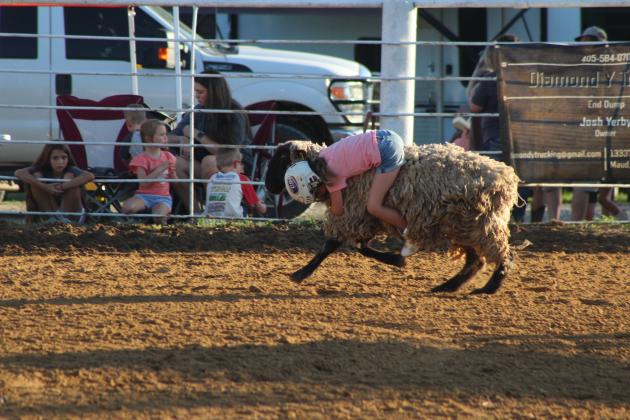 Raelynn Simmons of Shawnee hugs her sheep around the neck in the Mutton Bustin' event of the 79th Annual Maud Roundup Rodeo, held at the Maud Rodeo Arena on July 18th and 19th. Kids could also participate in the Calf Scramble and money in the dirt on both days.