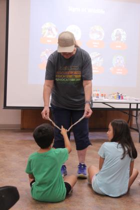 Wildcare OK long-time volunteer Debbie Saltzman holds a snakeskin for children to feel during the "Mammals in Your Back Yard" program at Shawnee Public Library on July 1.