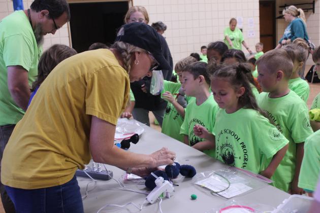 Ronda Cooper, from the Jasmine Moran Children's Museum in Seminole, hot glues googly eyes onto a 'Muttigrees' buddy for a girl during the Tecumseh Public Library event on July 17.