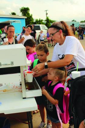 Brandi Driskill adds flavoring to the snow cones of Colt Driskill, 6, and Isabella Driskill, 4, during the Fifth Annual BancFirst Back to School Bash at the Harrison branch in Shawnee on July 31.