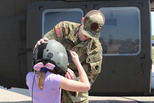 Sgt. Justin Donwerth closes the face shield on his helmet for Bellamy Martin, 9, of Shawnee, during Cops N' Kids on Aug. 23. Children could also sit in the Oklahoma Army National Guard Blackhawk UH60, in background, which flew into Shawnee out of Tulsa.