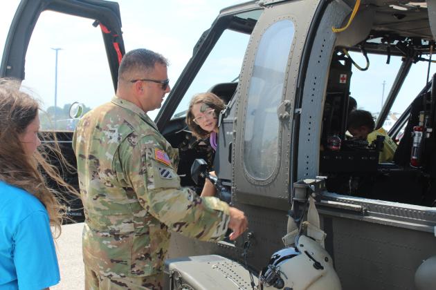 Oklahoma Army National Guard Pilot William Shufeldt tells Hadlee Farmer, 9, of Shawnee, about the Blackhawk UH60, as well as the helmet and vest she can try on, as her sister Bailee Farmer, 11, looks on, during Cops N' Kids on Aug. 23. Shufeldt said they flew in from Tulsa for the event at the Heart of Oklahoma Expo Center.