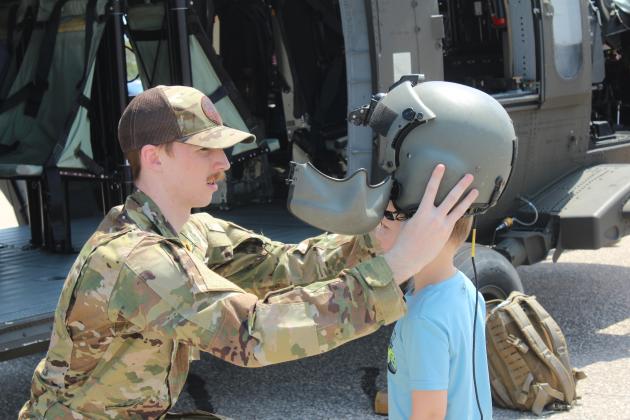 Sgt. Justin Donwerth places his helmet on Kaysen Meece, 4, of Texas, during Cops N' Kids on Aug. 23. Children could also sit in the Oklahoma Army National Guard Blackhawk UH60, in background, which flew into Shawnee out of Tulsa. An estimated 2,000 people attended the event at the Heart of Oklahoma Expo Center, said Founder and Coordinator Shawnee Police Cpl. Vivian Lozano-Stafford in an email.