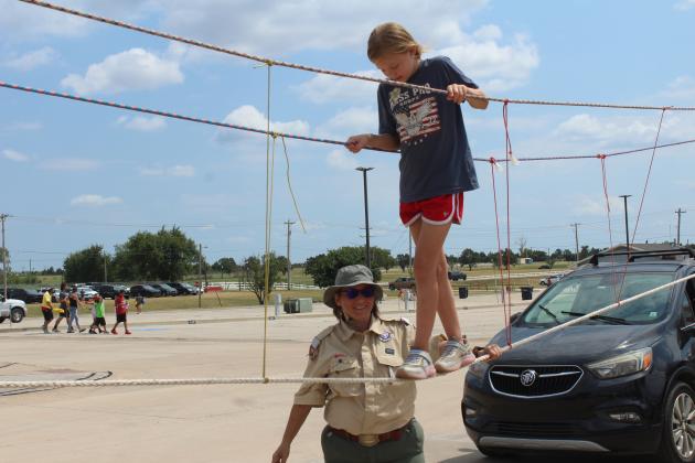 Iris Stewart, 10, of Shawnee, walks on a rope bridge, with the help of District Scout Leader Cindy White at Cops N' Kids on Aug. 23. White also leads the Female Scout Troop 6416 in McLoud.