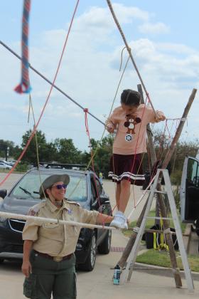 Gabby Hicks, 7, of Ada, walks on a rope bridge, with the help of District Scout Leader Cindy White at Cops N' Kids on Aug. 23. White also leads the Female Scout Troop 6416 in McLoud.