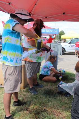 Vision Bank employees Alan Geiger, Andrew Meadows and Kim Haney create tie-dye T-shirts for a long line of people at Cops N' Kids on Aug. 23.
