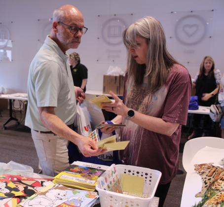Sequoyah Elementary fifth-grade teachers Brent Simmons and Britney Baker look through a basket of stickers during the Pack the School event for teachers to stock up on school supplies, held at First United in Shawnee on Aug. 8.