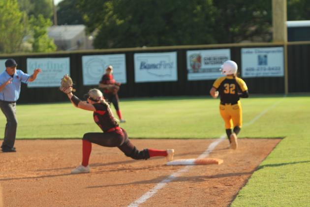 McLoud junior Avery Soward lunges to make the catch, as Tecumseh senior Cadence Leba crosses first base during the game at Tecumseh on Sept. 18. The Lady Redskins won, 3-7.