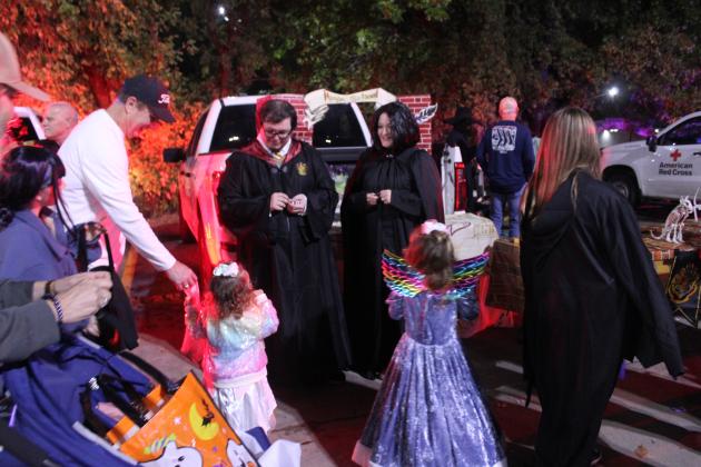 Citizen Potawatomi Nation/Pottawatomie County Dispatch Supervisor Katlyn Fry, right, and Dispatcher Kaleb Simons, left, give away candy during the Second Annual First Responders Trunk or Treat, held in the FireLake Arena parking lot on the evening of Oct. 25. Fry began the event last year, and this year, it had 2,453 visitors and between 20 and 30 local agencies participating.
