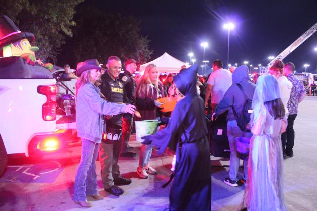 Shirley Wood, Pottawatomie County Sheriff Freeland Wood and Misty Moore add to trick-or-treaters' buckets. Also helping from the Sheriff's Office were David Brown and Matt Griffith. See full cutline below.