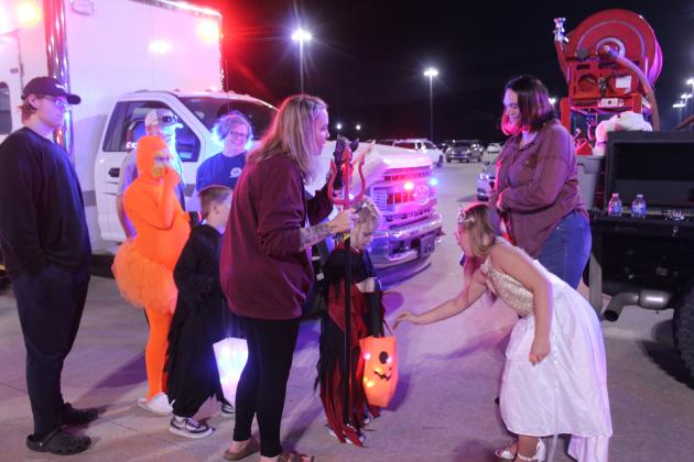Holly Morris, with the Tribbey Fire Department, far right, and her niece Annistyn Coughran, 8, hand out candy during the Second Annual First Responders Trunk or Treat, held at the FireLake Arena parking lot on the evening of Oct. 25. Also shown, in background,  are Tribbey Fire Chief and Pott. County Chair of Volunteer Fire Departments Mark Rodman and Mindy Rodman.