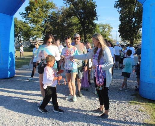 Tiffany Barrett hands out medals at the finish line of the Fourth Annual House of Hope Color Fun Run, held at the Citizen Potawatomi Nation Festival Grounds on Oct. 11. There were 547 people signed up for the event online, said Prevention Specialist Kayla Woody.