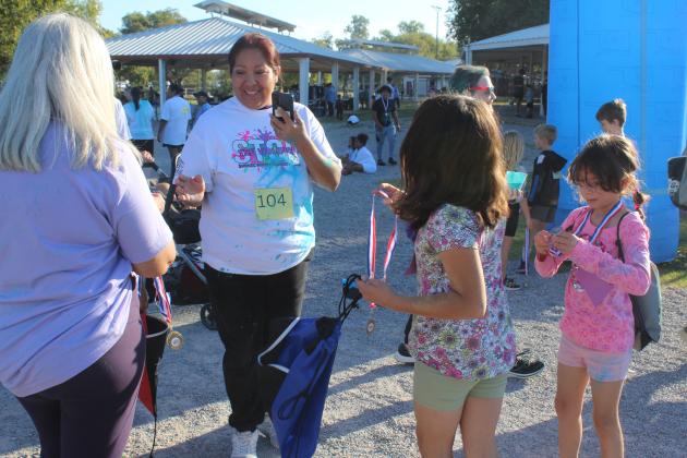 Leslie Collyer hands out medals at the finish line of the Fourth Annual House of Hope Color Fun Run, held at the Citizen Potawatomi Nation Festival Grounds on Oct. 11. There were 547 people signed up for the event online, said Prevention Specialist Kayla Woody.