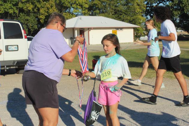 LaDawn Hladik hands out medals at the finish line of the Fourth Annual House of Hope Color Fun Run, held at the Citizen Potawatomi Nation Festival Grounds on Oct. 11. There were 547 people signed up for the event online, said Prevention Specialist Kayla Woody.
