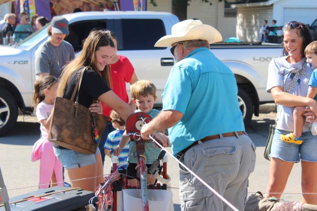 Madilynn Reeser of Asher and Danny Dunagan help Jackson Reeser, 3, to make a rope at the Shawnee Tractor and Engine Club booth during Tecumseh's Frontier Days on Sept. 27. They also offered corn shelling and water pumping in the Kids Zone. The theme for this year's Frontier Days was "Back to Our Roots."