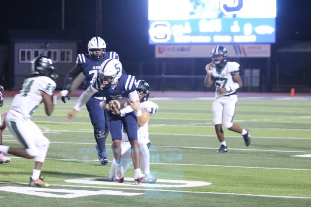Shawnee senior Braylon Lassiter is the ball carrier with the quarterback keeper for a first down and 10, despite being stopped in his tracks by an Edison Eagle, during the second quarter of the Oct. 23 homecoming game. The game was called at halftime due to lightning, but the Wolves won against Tulsa's Edison Prep 38-0.