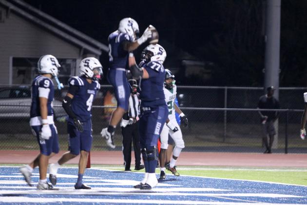 Shawnee senior Kaden Bramlage lifts fellow senior Tate McClendon in celebration of McClendon's touchdown in the second quarter of the Oct. 23 homecoming game. The game was called at halftime due to lightning, but the Wolves won against Tulsa's Edison Prep, 38-0. Athletic Director Dax Leone said both coaches agreed.