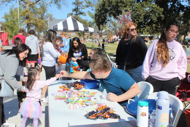 Isaiah Young, with Wesley United Methodist Church of Shawnee, hands a toy to a girl during the Shawnee Fall Festival at Woodland Veterans Park on Nov. 1. Also shown, standing, are Addison and Ava Jobson with the church. Shawnee Public Information Officer Jamie Sacco said they had 51 booths and five food trucks.