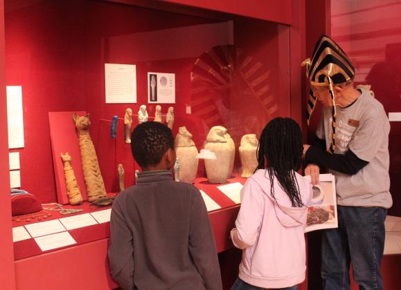 Mabee-Gerrer Museum of Art Docent Dick Trim speaks to two children about canopic jars and shows a picture of the mummified stomach contents in one during the Fifth Annual Mummy Day on Nov. 8. During the annual event, children could create Egyptian-themed crafts, learn from several experts like Trim and visit the two mummies at the museum in Shawnee.