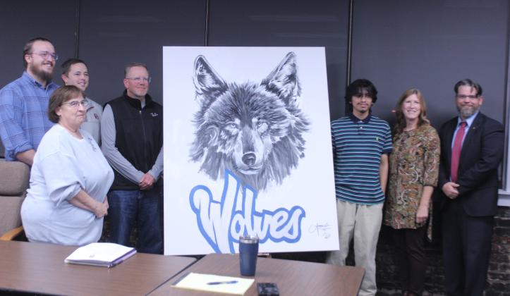 Shawnee High School senior Angel Cazares, third from right, painted this wolf to hang in the Shawnee Public Schools Board of Education room the day before the Nov. 3 meeting. Shown, from left, are board members Turner Bass, Mandy Hillhouse, Casey White, Russ Oliver, Cazares, Jeanne Swinney and President Clif Harden. Cazares also did a live painting of a wolf at the Oct. 21 Community Pep Rally. Natasha Dunagan, Countywide &amp; Sun