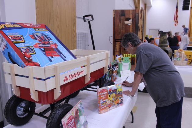 Jan Parker adds her silent auction bid during the Tecumseh FFA Pig Roast, held at the THS Alumni Center on Nov. 21. The fundraiser also included a live auction and student skits. FFA Advisor Mara Carmen said they sold 225 tickets for the annual event.