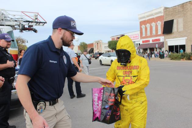Tecumseh Police Officer Zach Steingas gives candy to a "hazmat worker" during the Tecumseh Business Treat 'r Treat on Oct. 31.