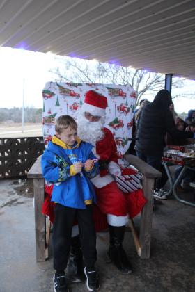 Natasha Dunagan, Countywide &amp; Sun Wyatt Fitzgerald, 10, holds the candy cane Santa gave him and considers what he really wants for Christmas during the Bethel Community Christmas Tree Lighting Ceremony on Dec. 7 at the Community Center Pavilion.