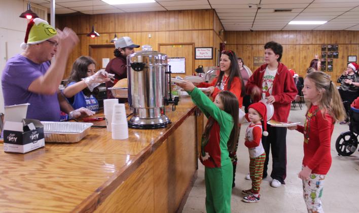 Greg Arbuckle, his granddaughter Cassidy Cellars and Justin Wood serve breakfast to a family during the First Annual Grinch-fast, held at the Veterans of Foreign Wars in Shawnee on Nov. 29. The family members, from left, are Stevie Scott, Bo Scott, Legend Scott, Ryder Buckmaster and Lexi Scott. Arbuckle and Clay Dodgion were volunteering with the Shawnee Lions Club. This was a fundraiser for the Pottawatomie County Giving Project, which has 618 children and adults with disabilities on their Christmas list.