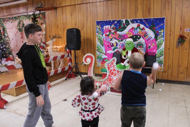 Out of "snowballs," Jaxtyn O'Neal, 10, watches as Kassi Fisher, 2; and Maddox Streeter, 6, aim fluffy snowballs at the Grinch during the First Annual Grinch-fast, held at the Veterans of Foreign Wars in Shawnee on Nov. 29. This was a fundraiser for the Pottawatomie County Giving Project, which has 618 children and adults with disabilities on their Christmas list this year.