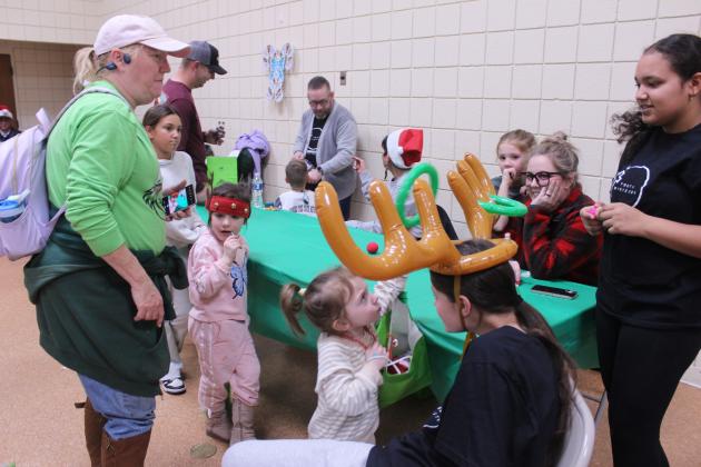 Patience Ring, 3, of Tecumseh, places a ring on inflatable antlers worn by Ali Thomas, as her mother Donna Bennett and sister, Mila Ring, 4, look on during the Whoville event in the Tecumseh City Hall Auditorium on Dec. 11. The reindeer ring toss was run by Grace Community Church. Tecumseh Chamber of Commerce Executive Director Kim Elliott estimates that 1500 people visited Whoville.