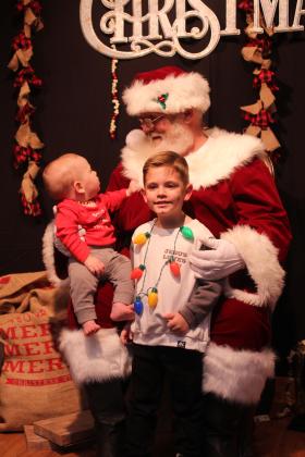 Seven-month-old Bodie Faulks takes a good look at Santa Claus, as his brother, Mason Faulks, 4, both of Tecumseh, poses during the Whoville event in the Tecumseh City Hall Auditorium on Dec. 11.
