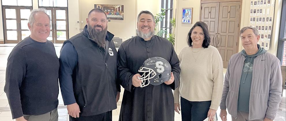 On Dec. 5, Shawnee Wolves Football Head Coach Jason Madonna presented St. Benedict's Church Very Rev. Christopher Brashears, pastor, and Danielle Roberts, office manager, with a helmet autographed by the football team players. See full cutline below.