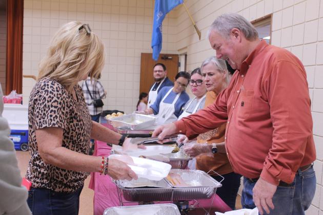 Tecumseh Family Thanksgiving event co-founder, Randy Gilbert, right, adds turkey to a dinner being served by volunteer Carol Bass during the 20th Anniversary dinner, held at the Tecumseh City Hall Auditorium on Nov. 27.