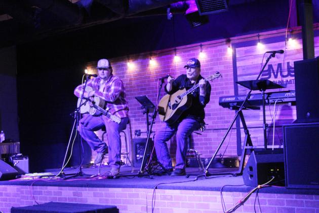 Ed Combs, right, signals to the crowd for their audience participation moment during his song, "Rocking Chair, Cane Slip Blues," as Jacob McElroy looks on for Singer-Songwriter Night at Music Unlimited on Jan. 2. The event restarted in September 2025 and will continue on the first Friday of each month at 7 pm. Natasha Dunagan, Countywide &amp; Sun