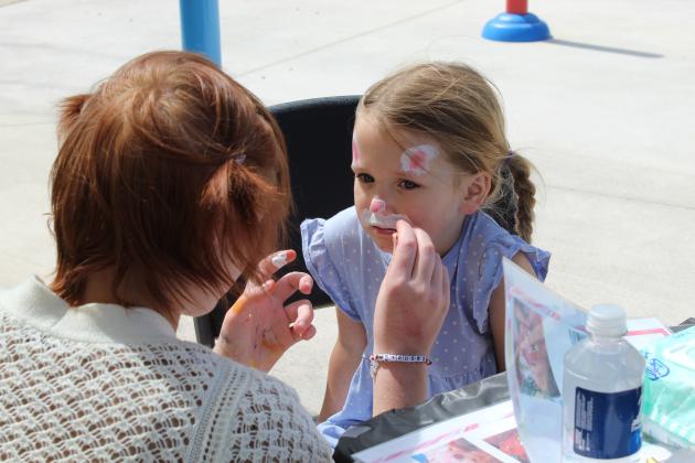 Alex Walley, from the Shawnee High School Academic Skills class, paints a bunny face on Bellamy Rains, 5, of Bethel, during the Community Renewal Easter Block Party on March 28 at Boy Scout Park in Shawnee. Rains is the daughter of Danielle Rains, who works with the schools on behalf of Community Renewal.